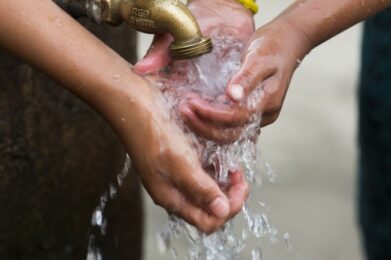 Two girls wash their hands at a public faucet in Santa Maria, Guatemala.